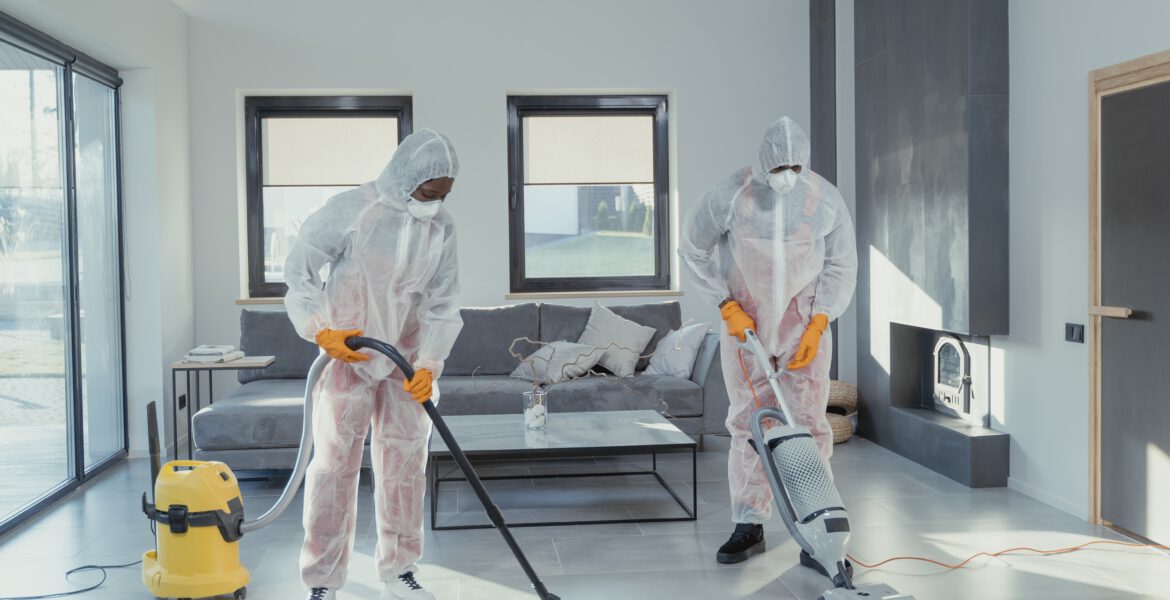 Dwoje pracowników firmy sprzątającej ubranych w specjalne kombinezony sprzątający mieszkanie