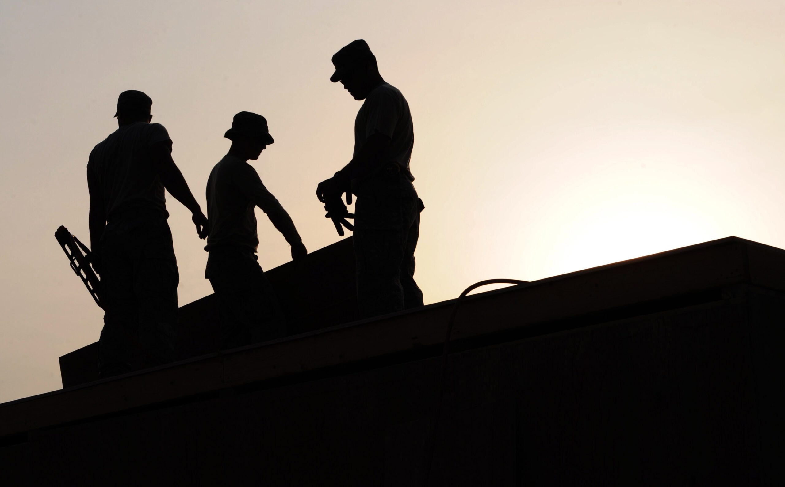 Pracownicy budowy na wysokościach na tle zachodzącego słońca