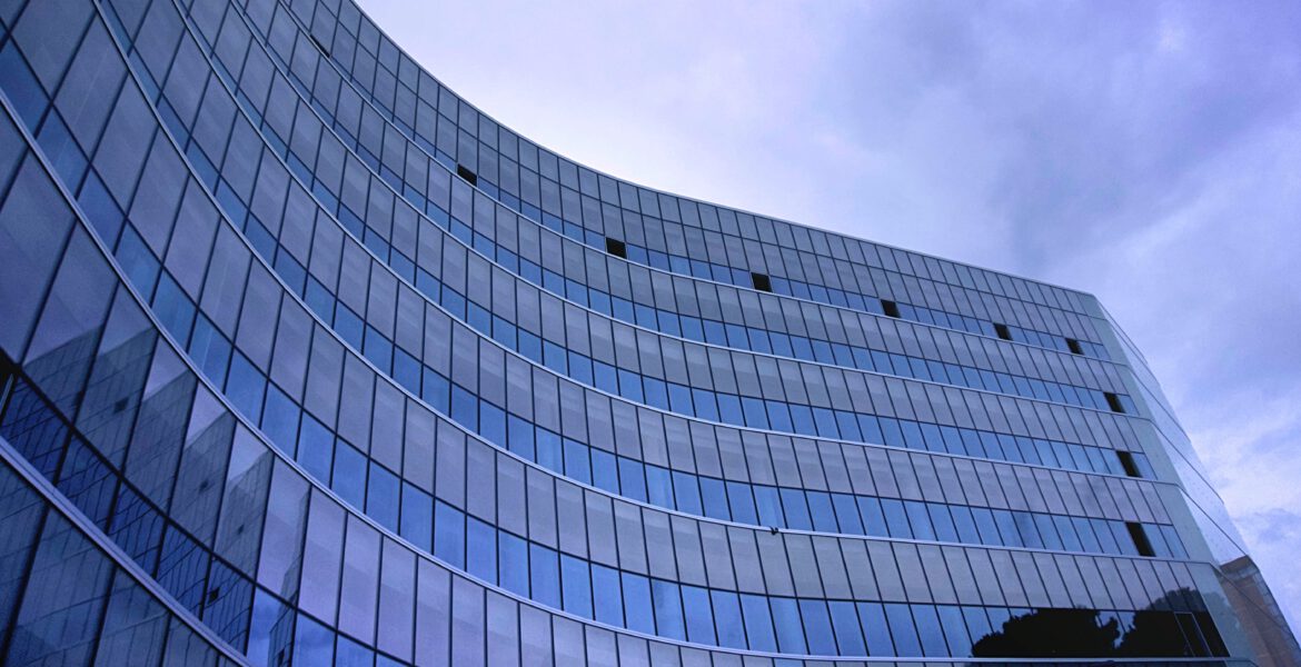 Wysoki szklany budynek firmy na tle niebieskiego nieba