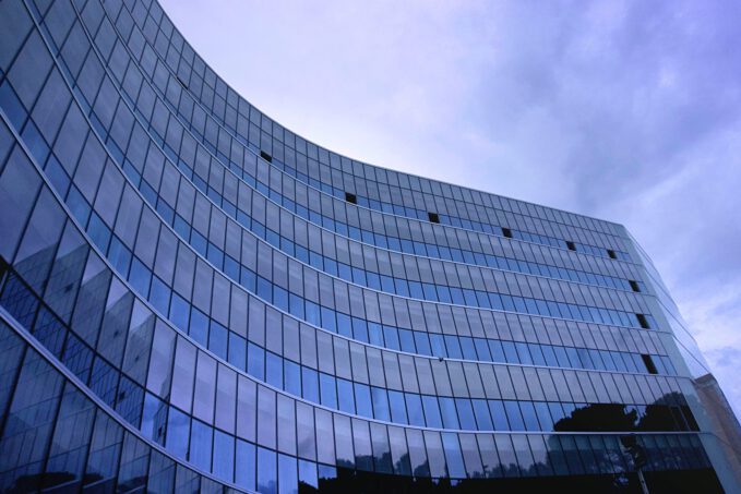 Wysoki szklany budynek firmy na tle niebieskiego nieba